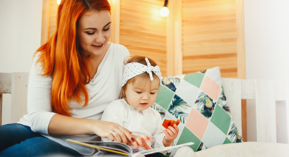 Une nounou lit un livre à un bébé.